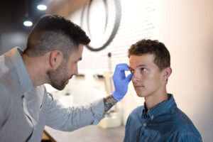 Ocularist Dwayne Collins inserting an artificial eye into a patient’s eye socket